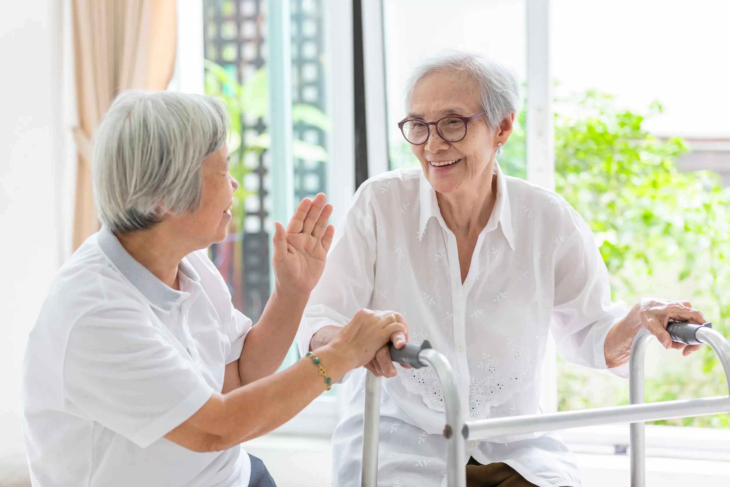 Happy two asian senior women friends holding hands for care,support and fun talking,time together